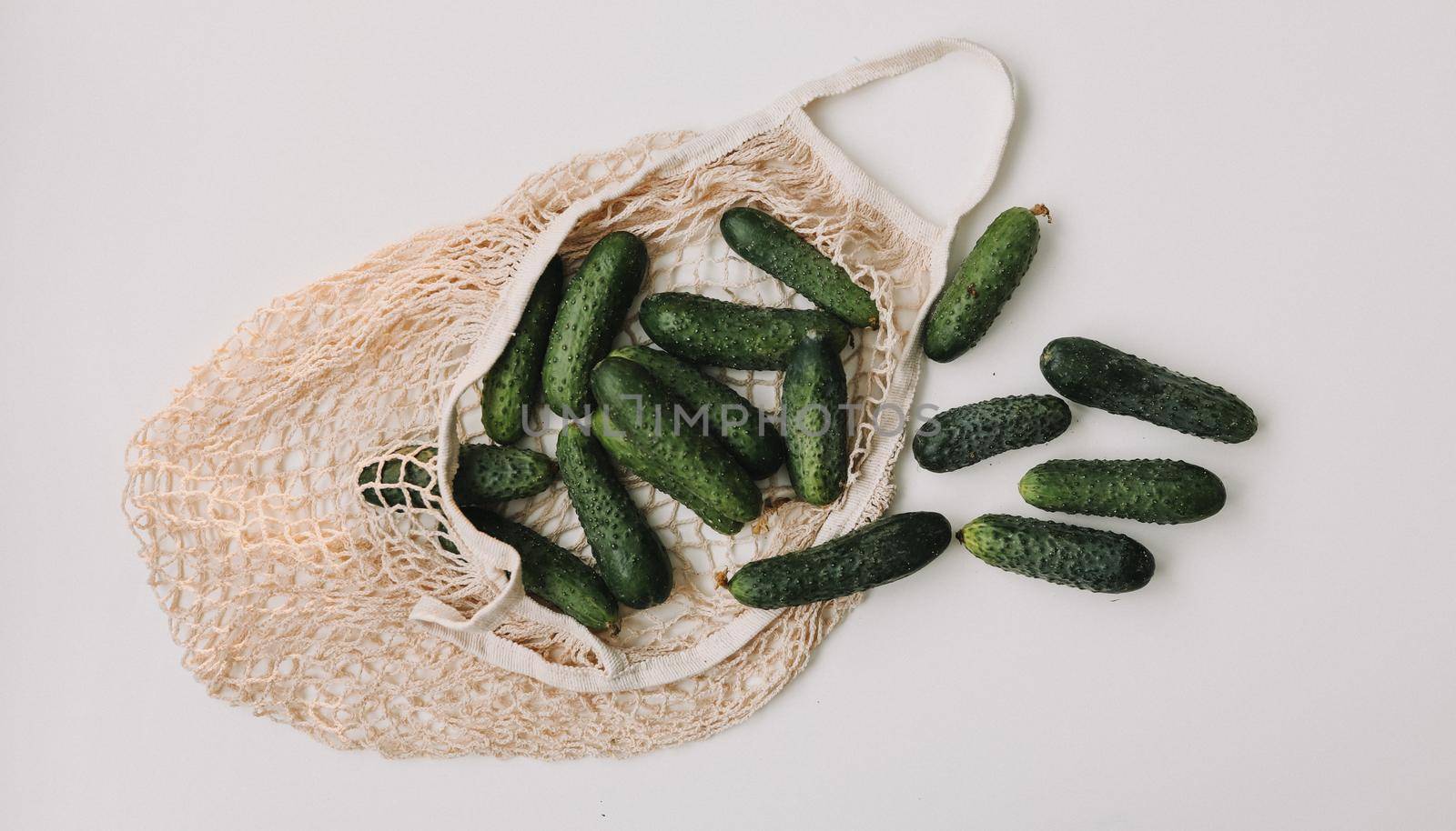 Green fresh cucumbers in a string bag isolated on white background. Concept zero waste. Top view. Flat lay.