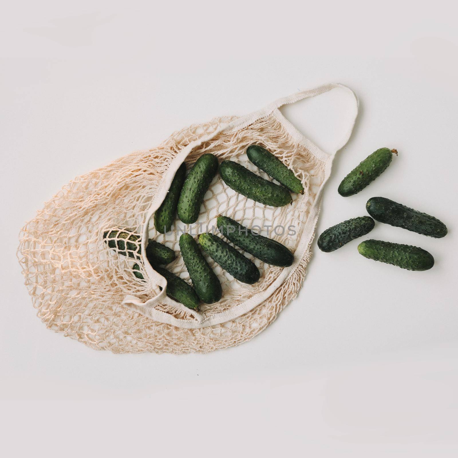 Green fresh cucumbers in a string bag isolated on white background. Concept zero waste. Top view. Flat lay.