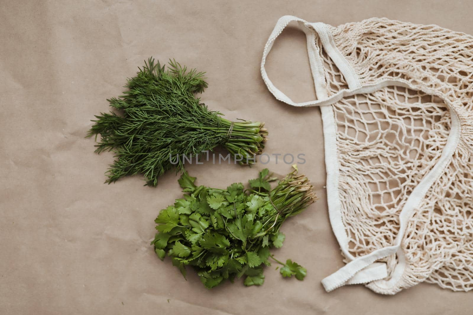 Bunches of fresh greens and organic herbs on beige background. Healthy food. Flat lay, top view, copy space.