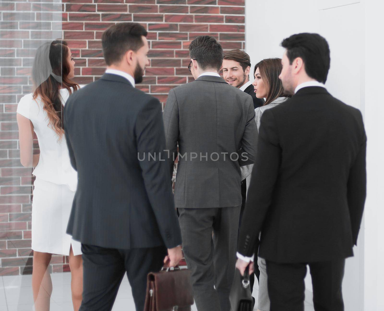 group of business people talking, standing in the lobby of the business center. by asdf