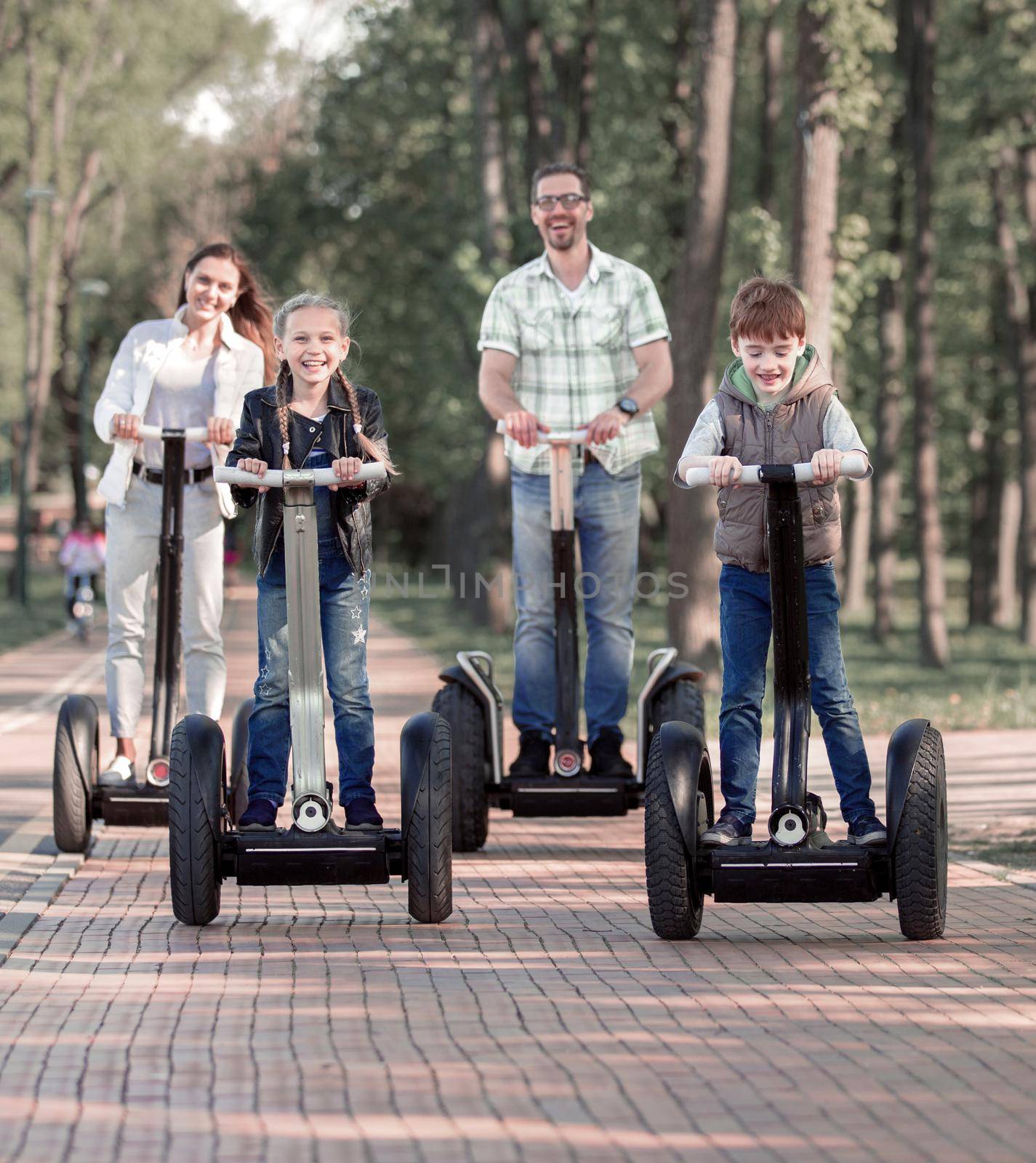 happy family riding electric scooters in the Park by asdf