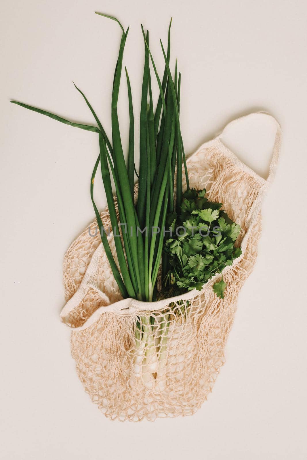 Fresh green onions in eco friendly bag on white background top view, flat lay. Healthy organic food. Zero waste shopping concept.