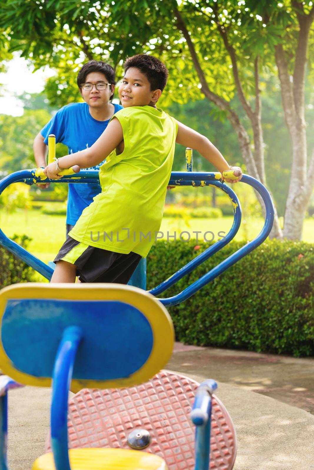 Child playing on outdoor playground. Kids play on school or kindergarten yard. Active kid on colorful swing. Healthy summer activity for children. Little boy swinging in tropical garden by Benzoix
