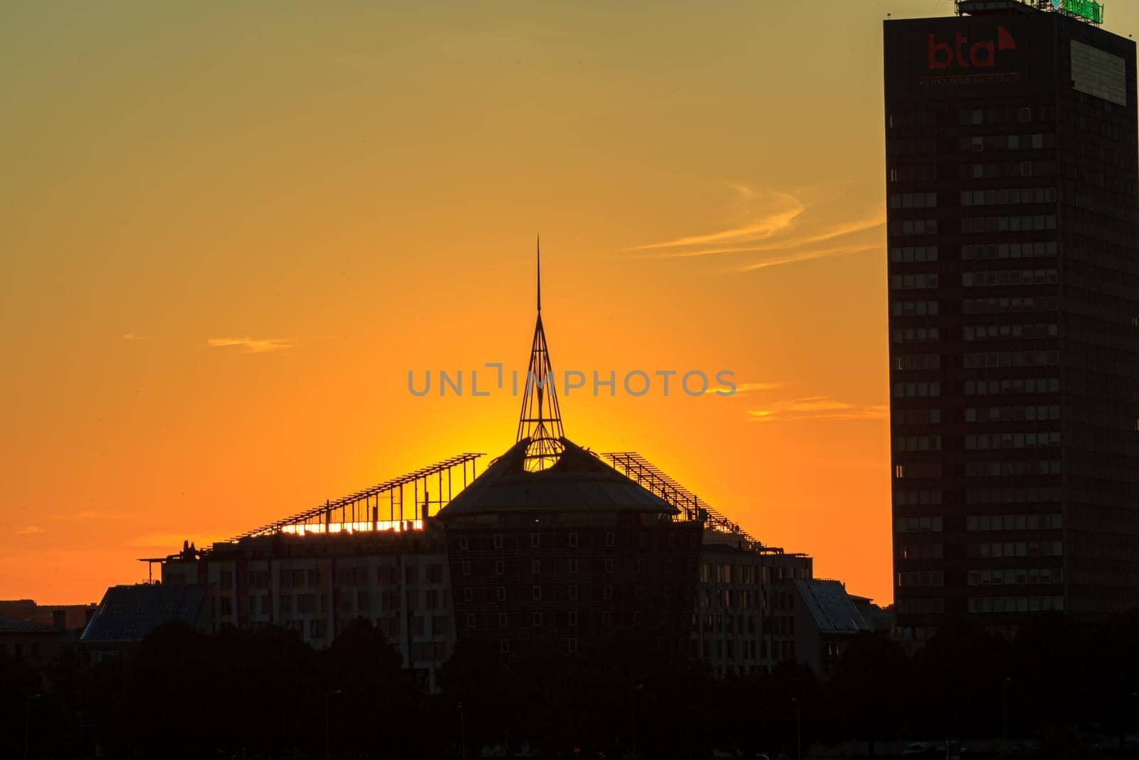 Riga, Latvia- July 17 2020: city architecture at sunrise time, orange sky, skyscaper building
