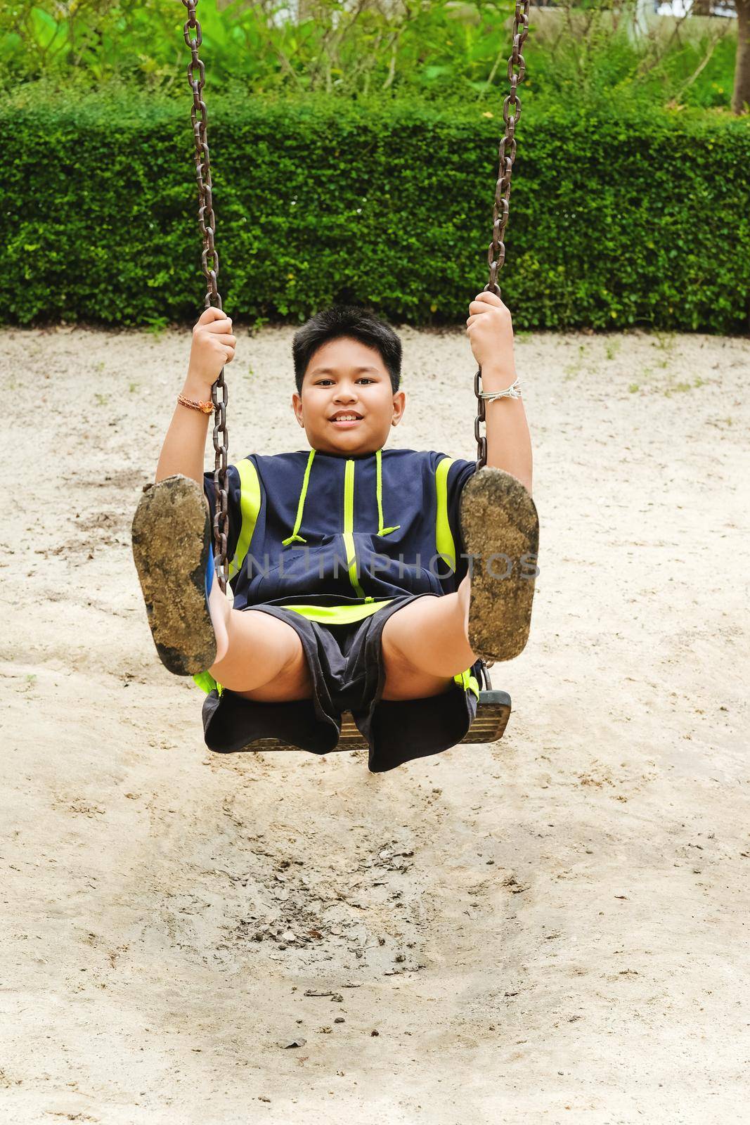 Happy asian sport boy play on swing playground in Garden. by Benzoix