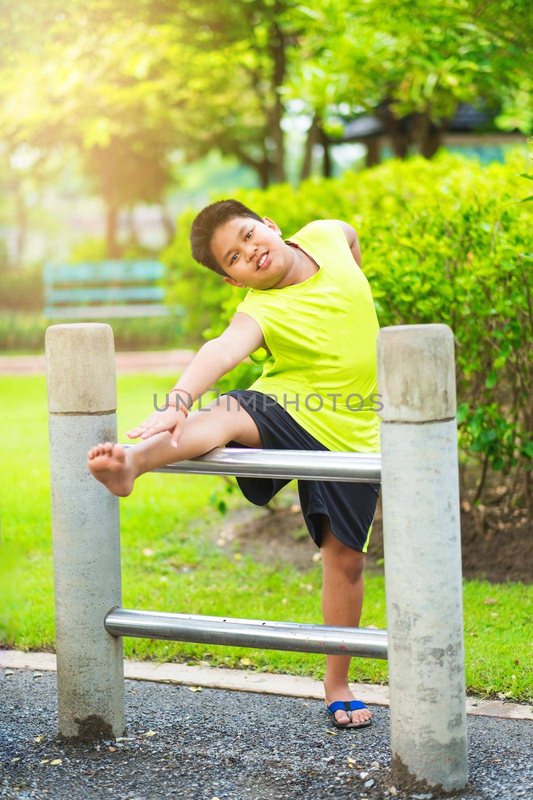 Asian sport boy stretching on iron bar in garden by Benzoix