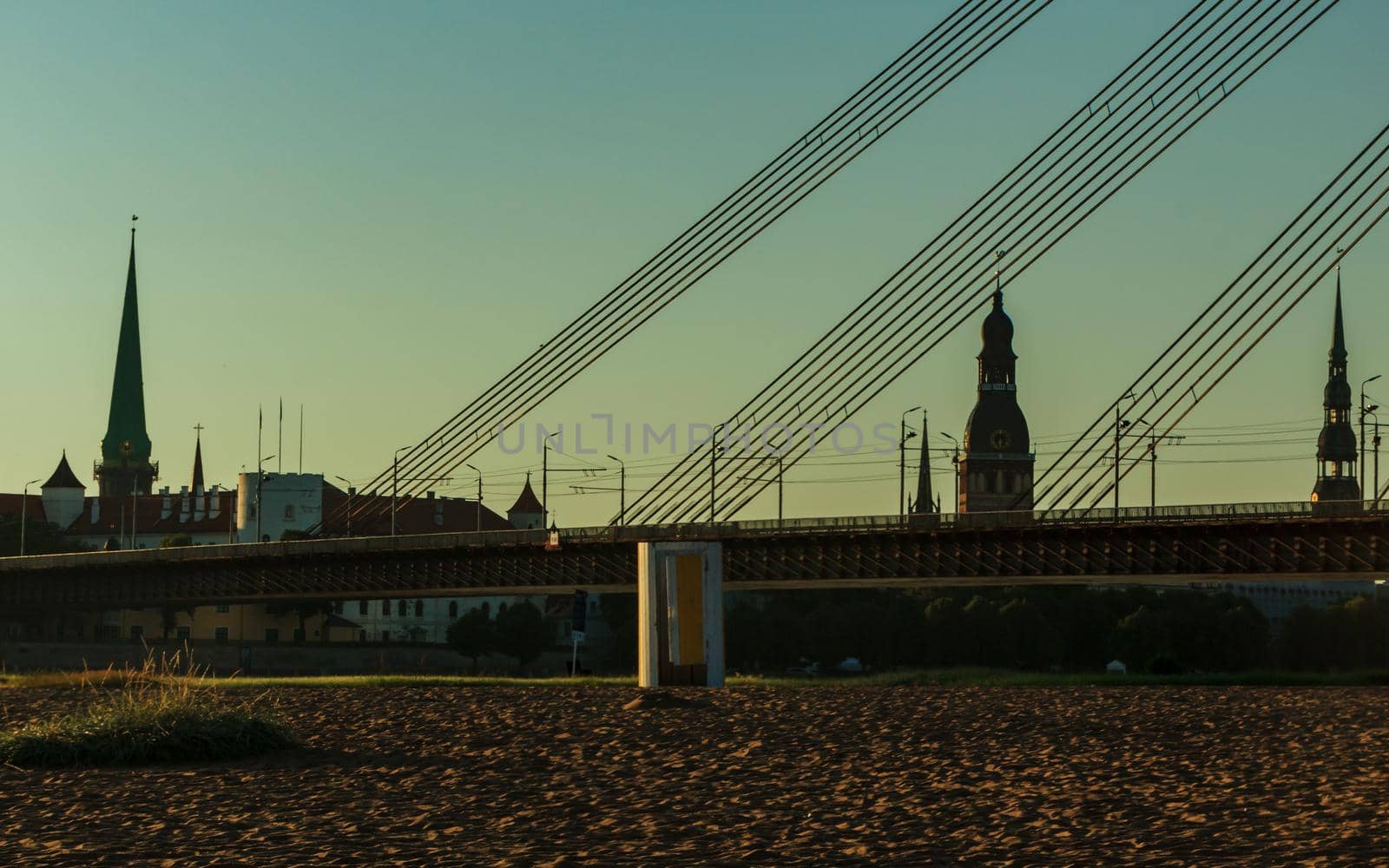 Riga, Latvia- July 17 2020: capital city bridge and architecture buildings view at sunrise time, beach sand foreground