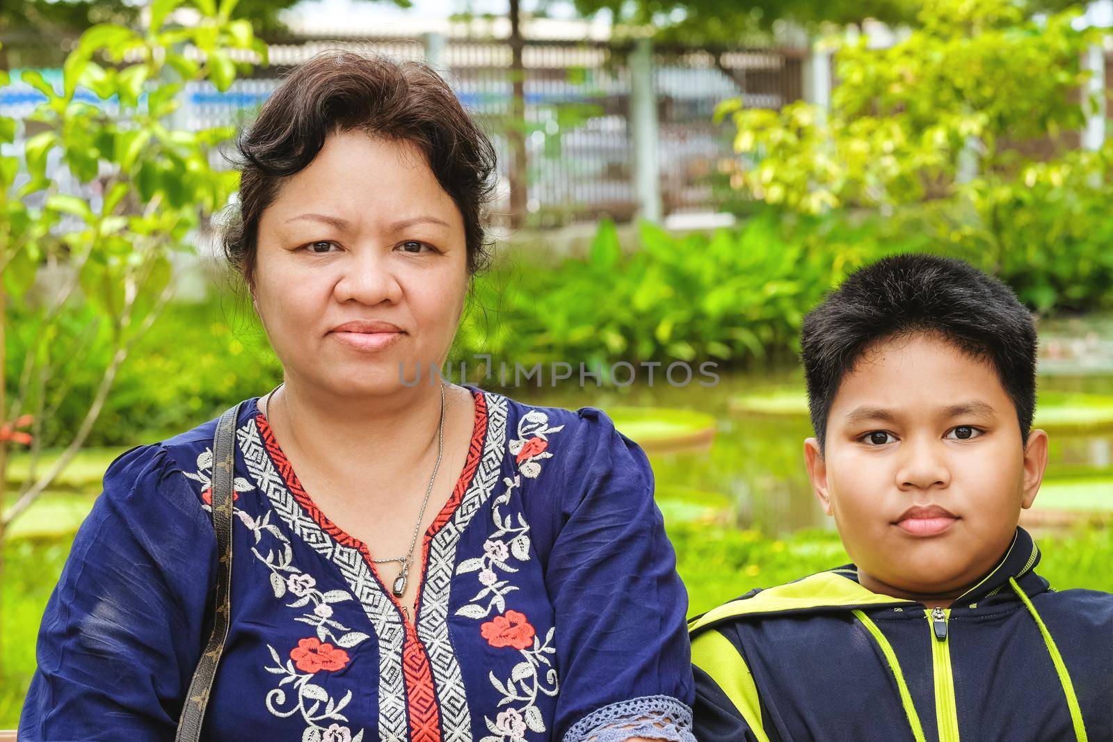 Happy asian woman, mother sitting with her son and sitting in the park.