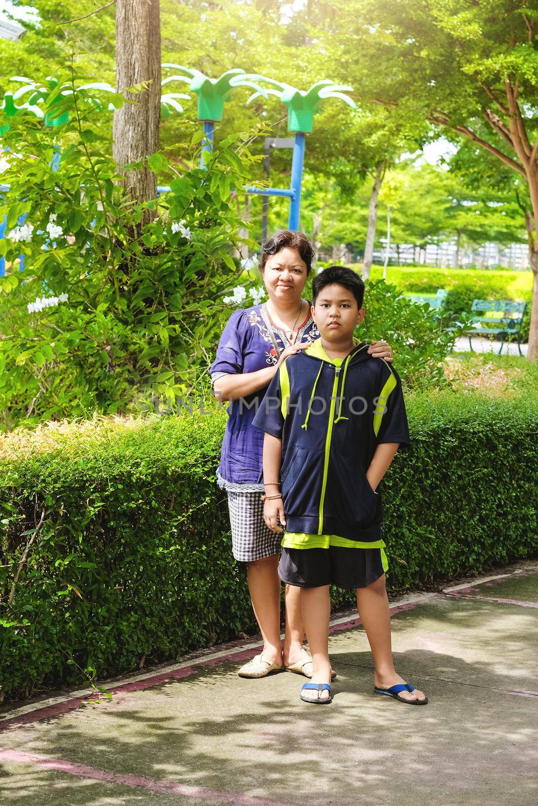 Little cute asian boy with her mom in the garden. by Benzoix