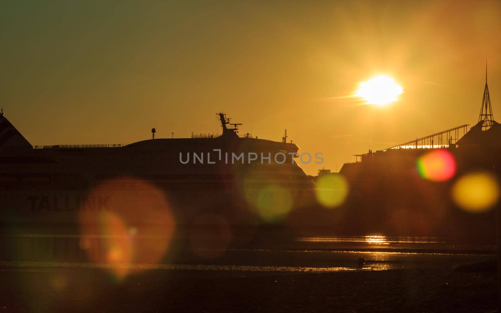 Riga, Latvia- July 17 2020: city beach near river, Tallink cruise ship view at sunrise time, colorful lens flare effect