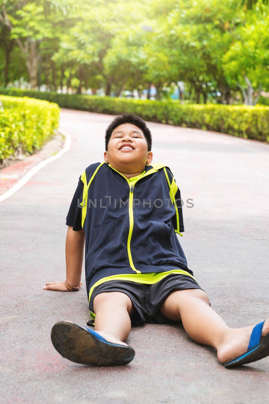 Selective focus at young Asian boy sit and tired on track after running