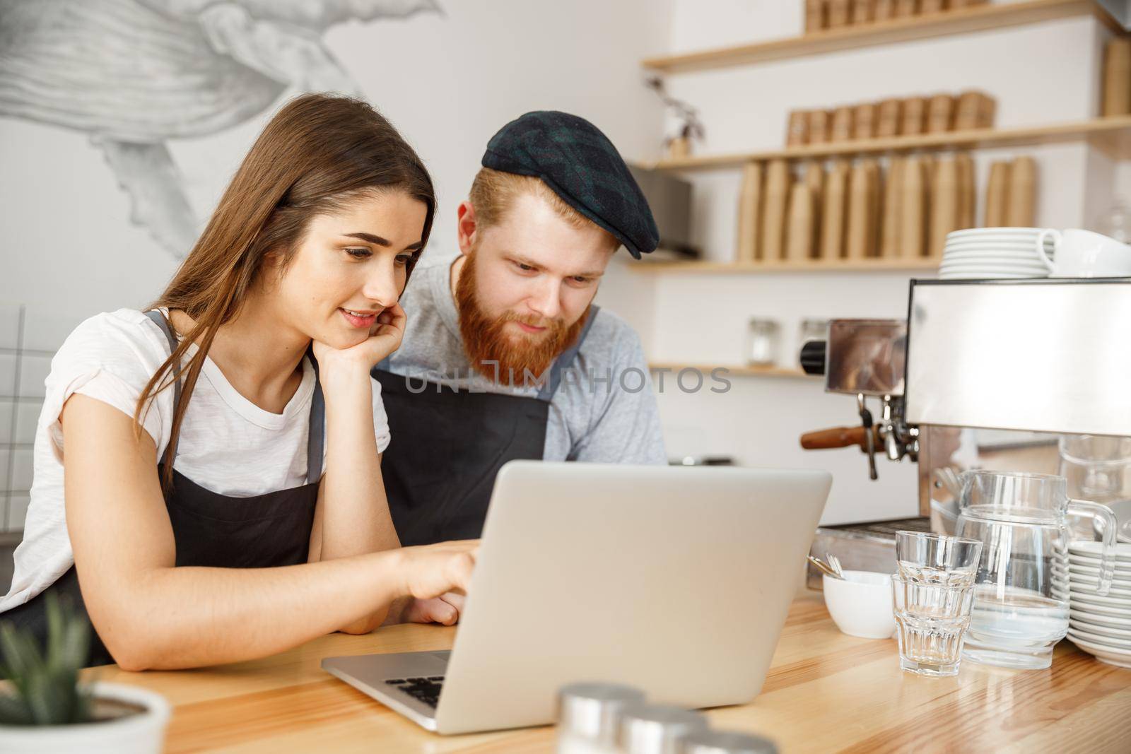 Coffee Business Concept - Satisfied and smile owners look on laptop for online orders at coffee shop