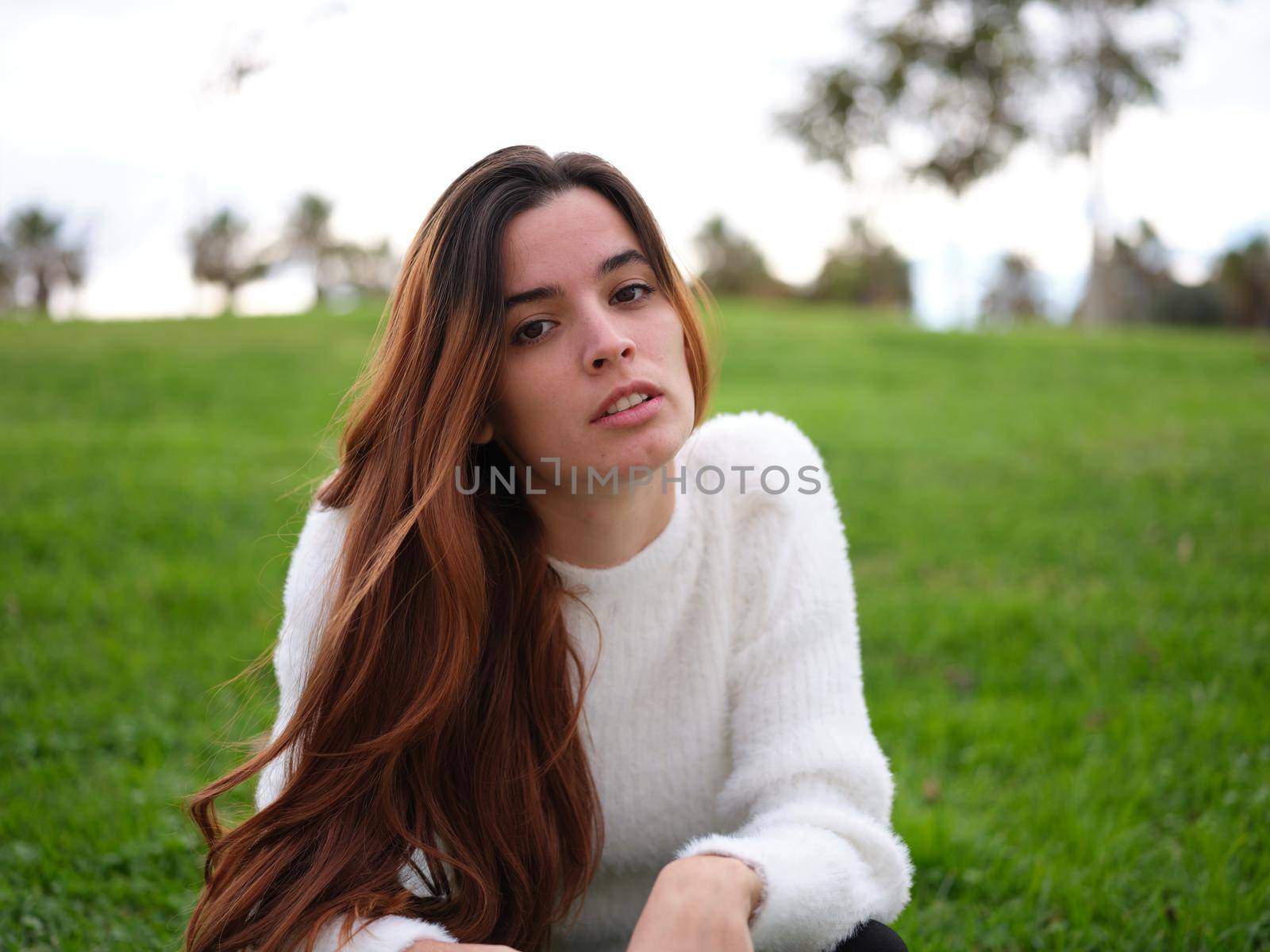 Front view of a young woman in the park looking at the camera seriously with a revengeful expression. Concept of emotions.