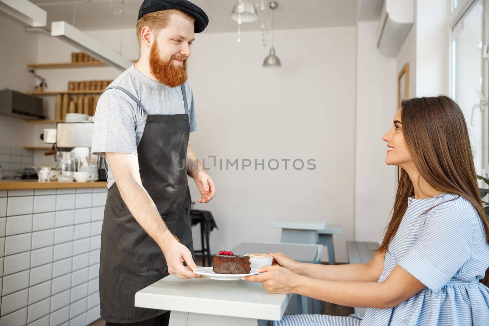 Coffee Business Concept - Waiter or bartender giving chocolate cake and talking with caucasian beautiful lady in blue dress at Coffee shop.