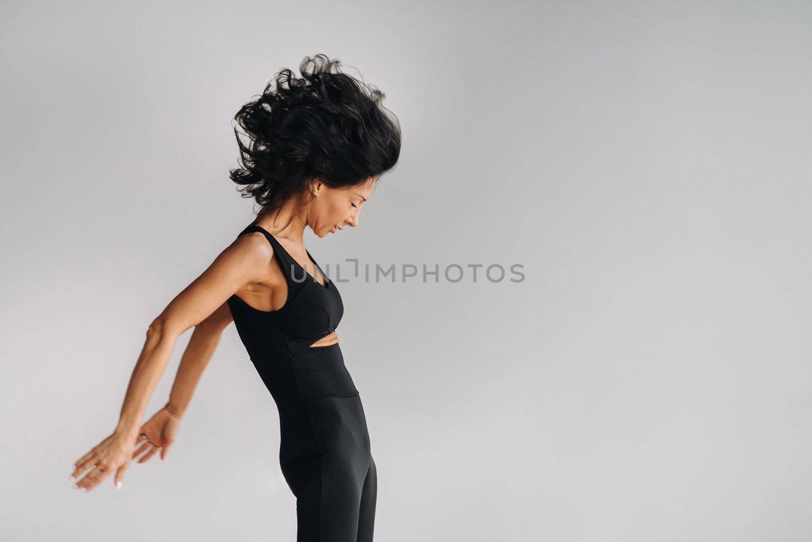 A woman in black sportswear is engaged in dynamic kali meditation in the Yoga hall.