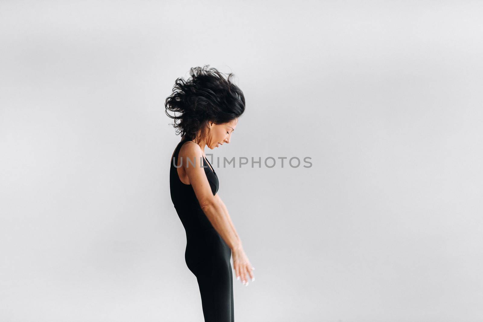 A woman in black sportswear is engaged in dynamic kali meditation in the Yoga hall.