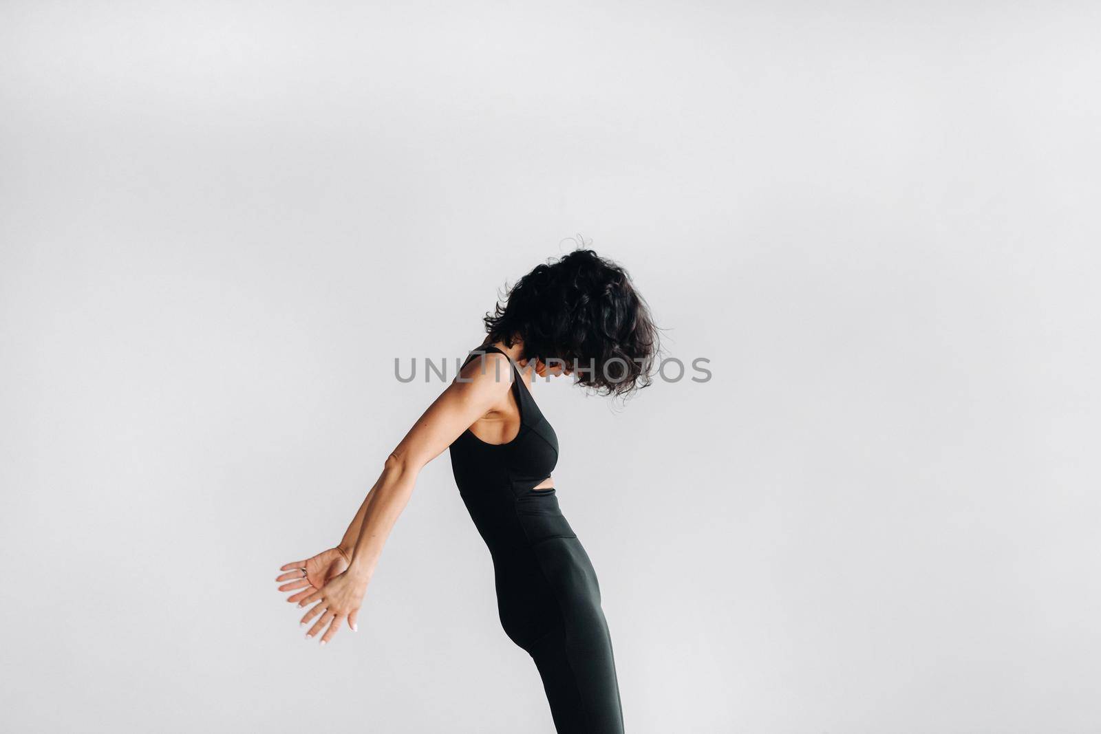 A woman in black sportswear is engaged in dynamic kali meditation in the Yoga hall.