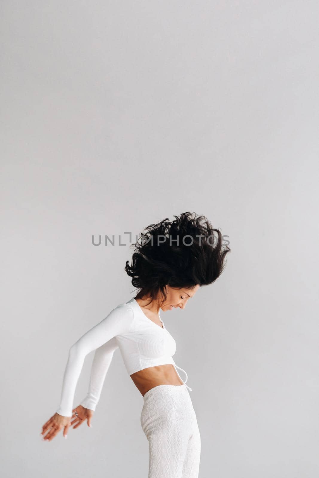 A woman in white sportswear is engaged in dynamic kali meditation in the yoga hall by Lobachad