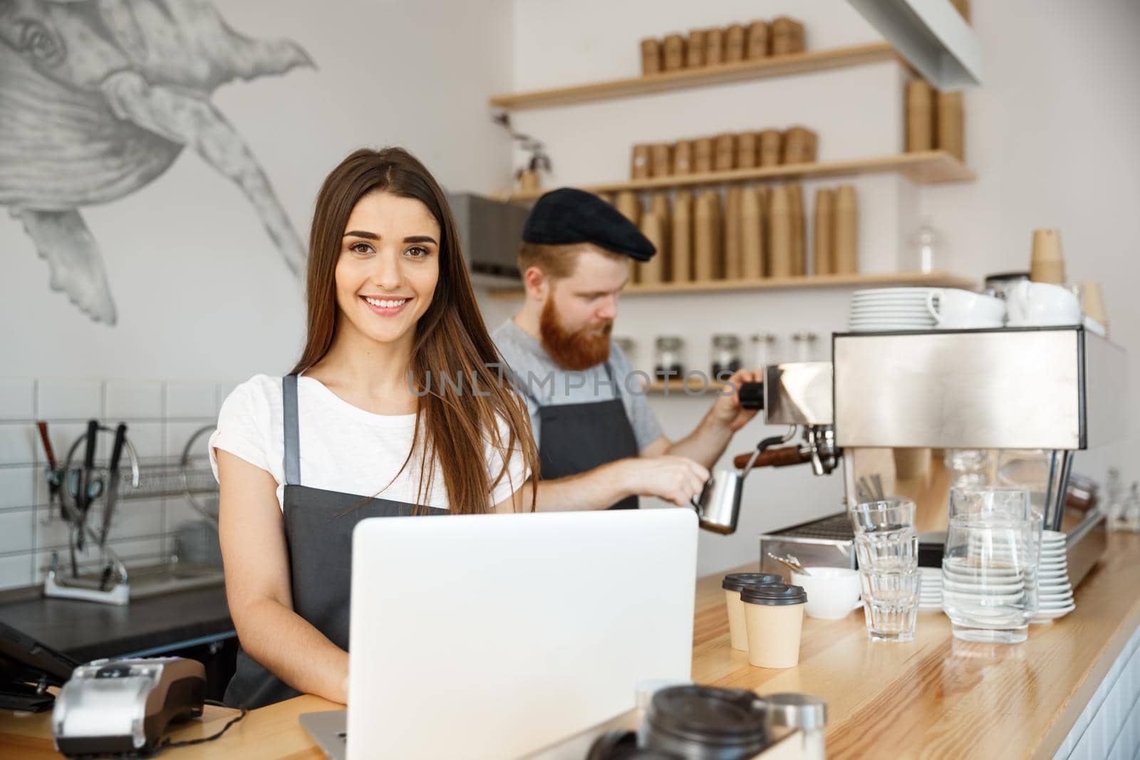 Coffee Business Concept - beautiful caucasian bartender barista or manager working and planing in laptop at modern coffee shop.