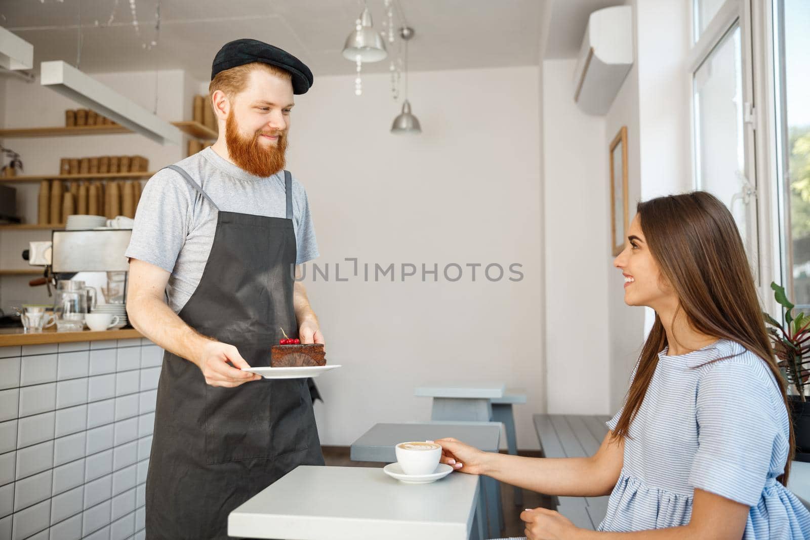 Coffee Business Concept - Waiter or bartender giving chocolate cake and talking with caucasian beautiful lady in blue dress at Coffee shop.