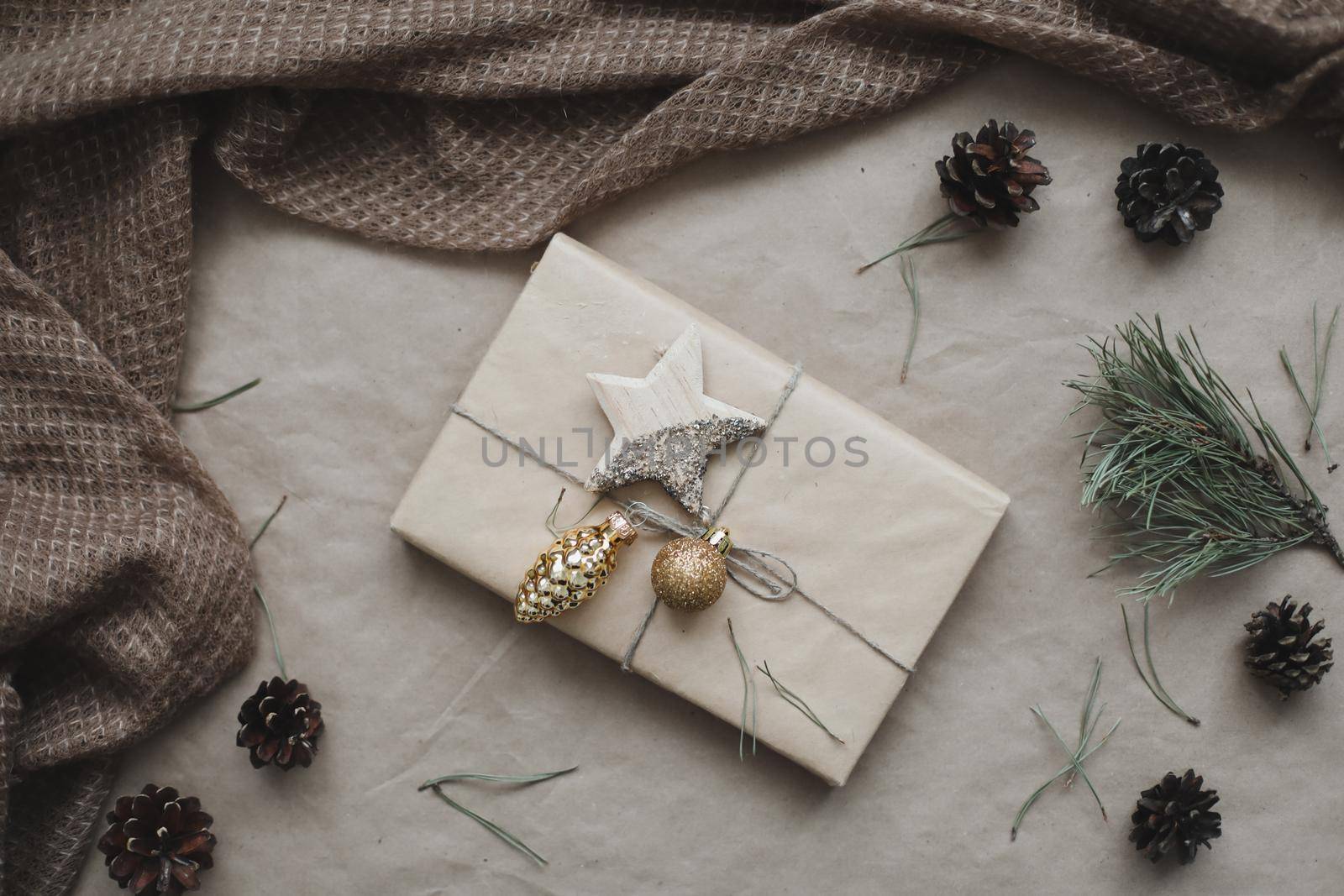 Christmas composition. Gift, fir tree branches, balls on craft paper background. Christmas, winter, new year concept. Flat lay, top view, copy space.