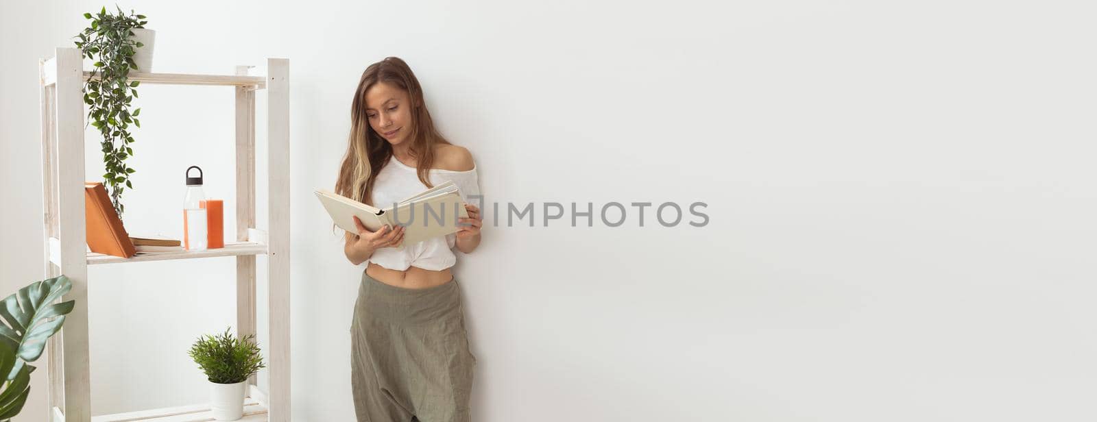 Young woman looking photo album at home. Memories and leisure banner white background with copy space by Satura86