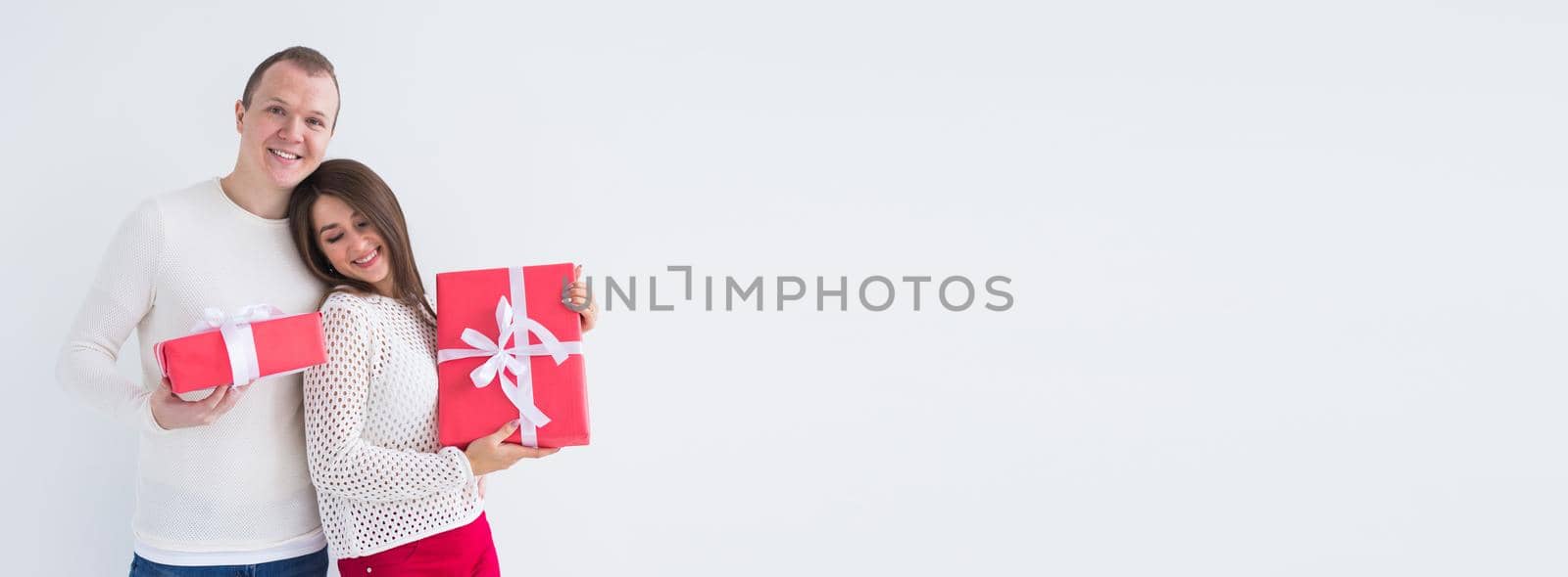 Christmas, holidays, Valentine's day and birthday concept - Happy man and woman holds boxes with gifts on white background banner with copy space by Satura86