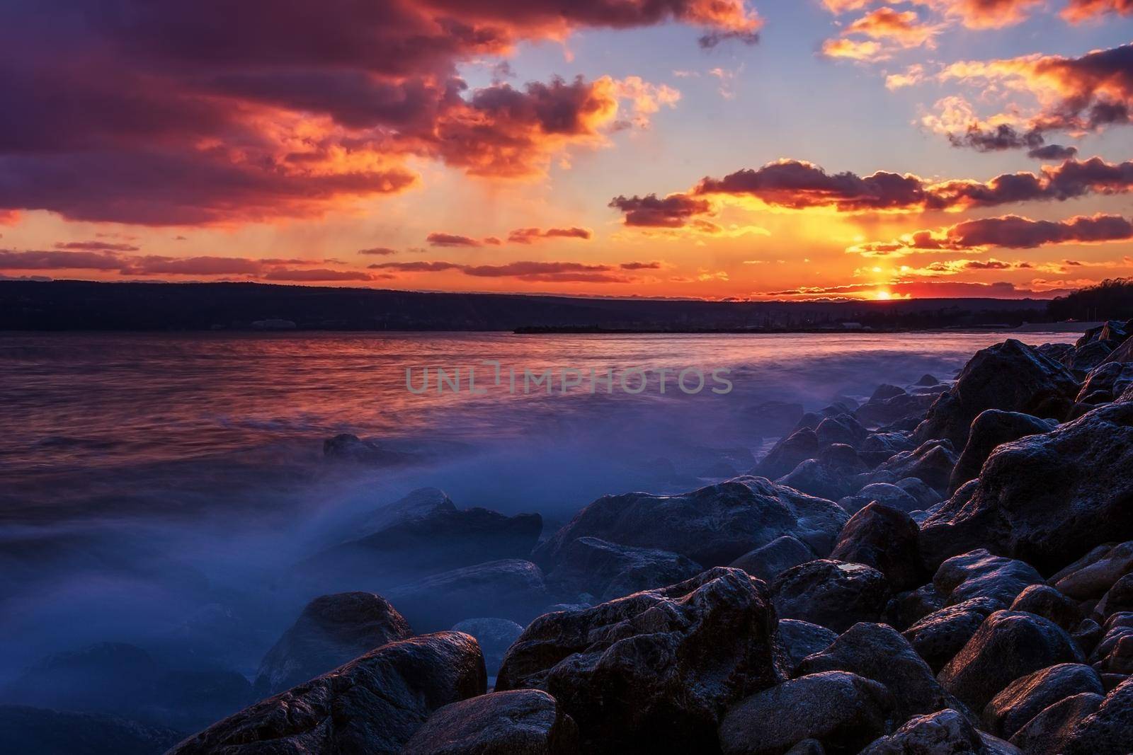 Sunning long exposure sunset over the sea with a rocky beach.