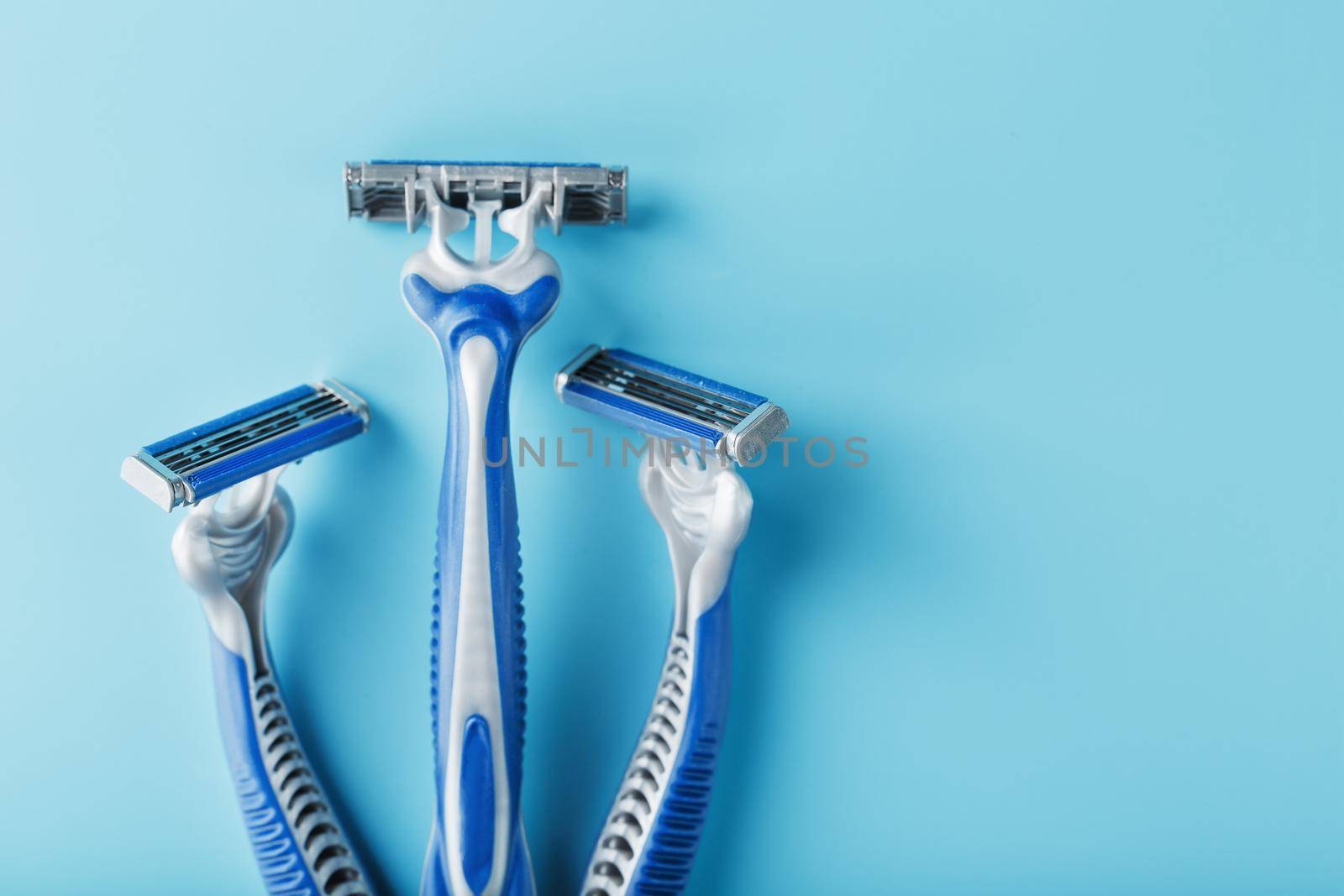 Three shaving machines on a blue background with free space, top view