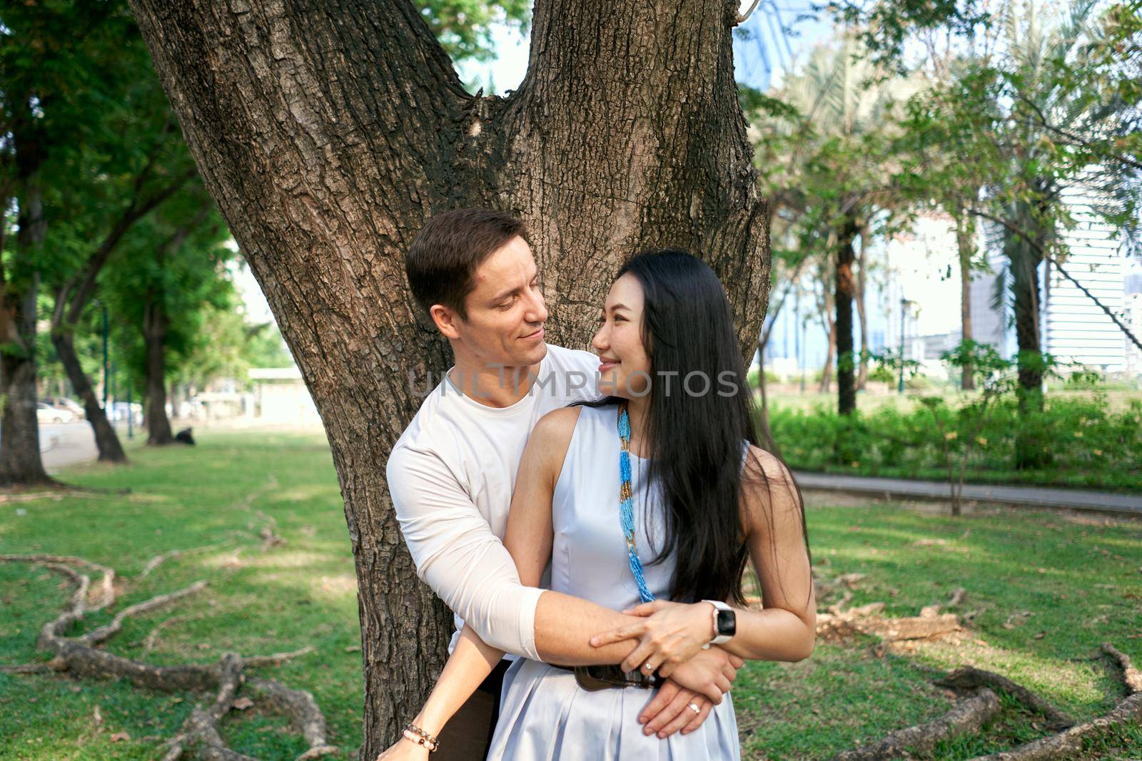 Close up portrait of a newly married couple embracing next to a tree in a park