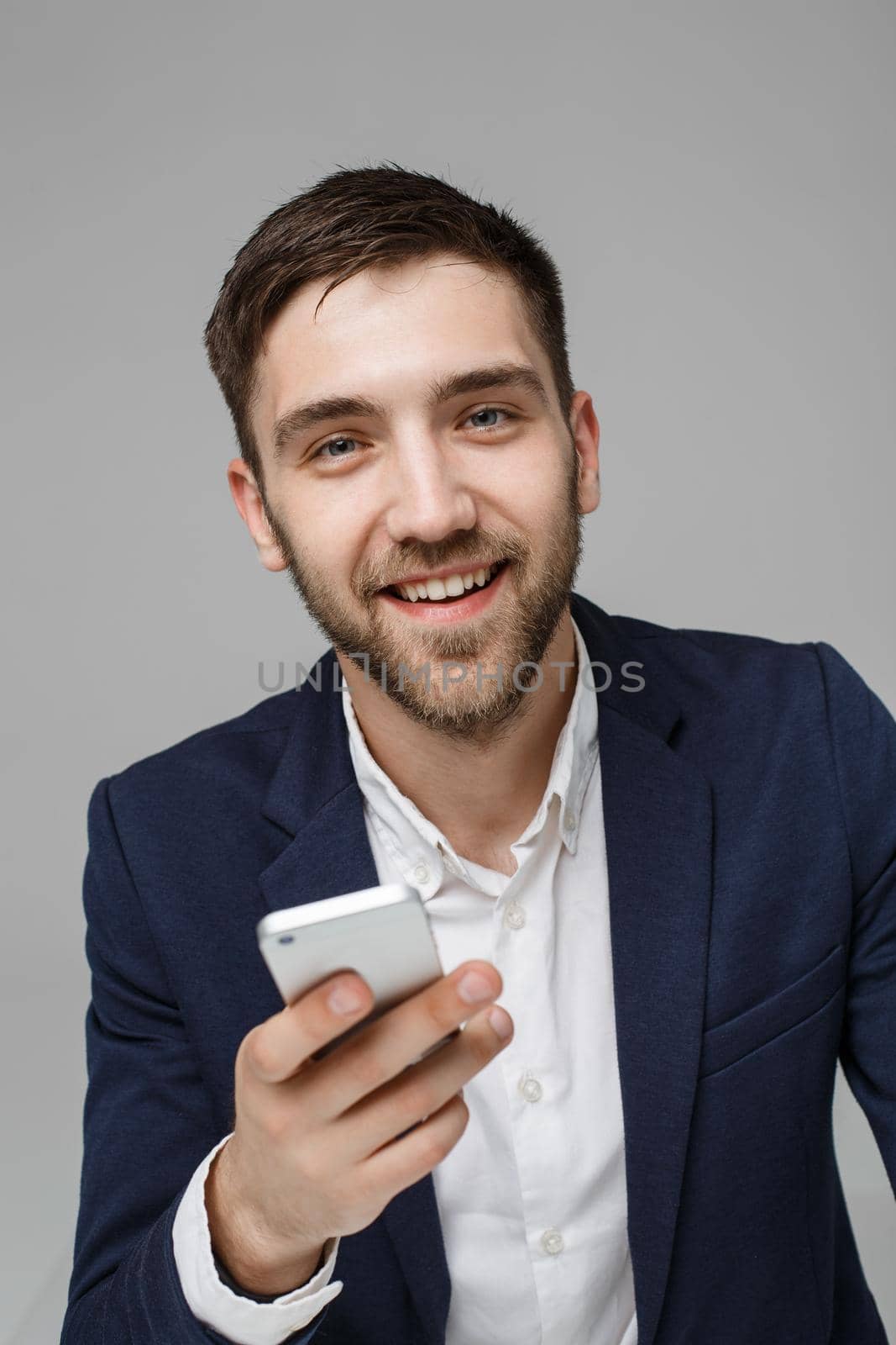 Business Concept - Portrait Handsome Business man playing phone with smiling confident face. White Background.Copy Space. by Benzoix