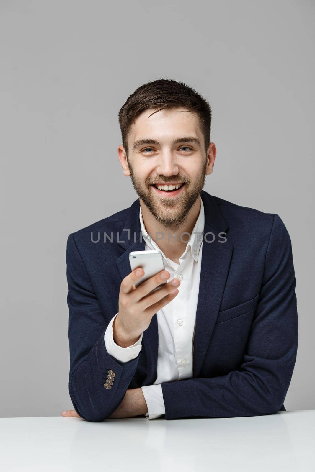 Business Concept - Portrait handsome happy handsome business man in suit playing moblie phone and smiling with laptop at work office. White Background. by Benzoix