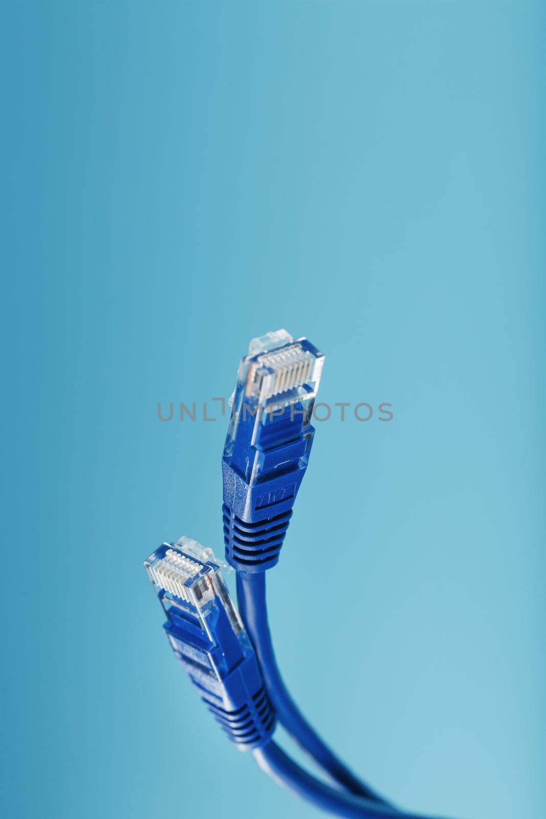 Two Ethernet Cable Connectors Patch cord cord close-up isolated on a blue background with free space by AlexGrec