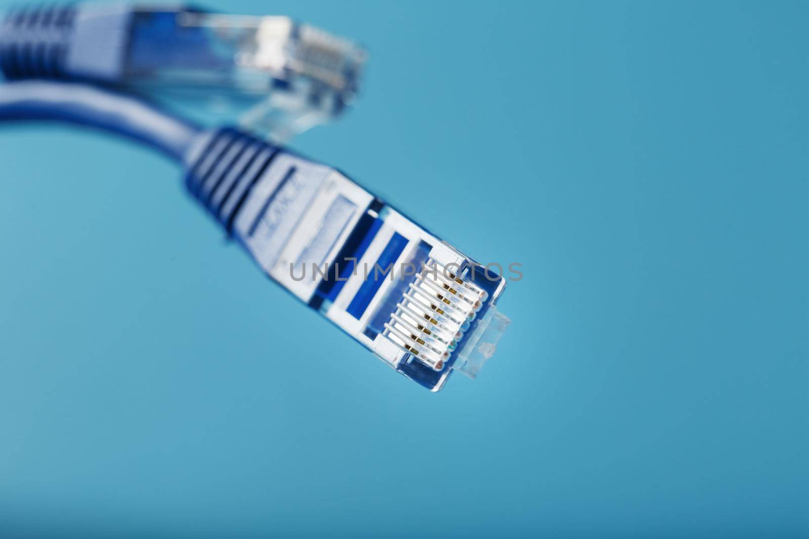 Blue Ethernet Cable Connectors Patch cord cord close-up isolated on a blue background with free space