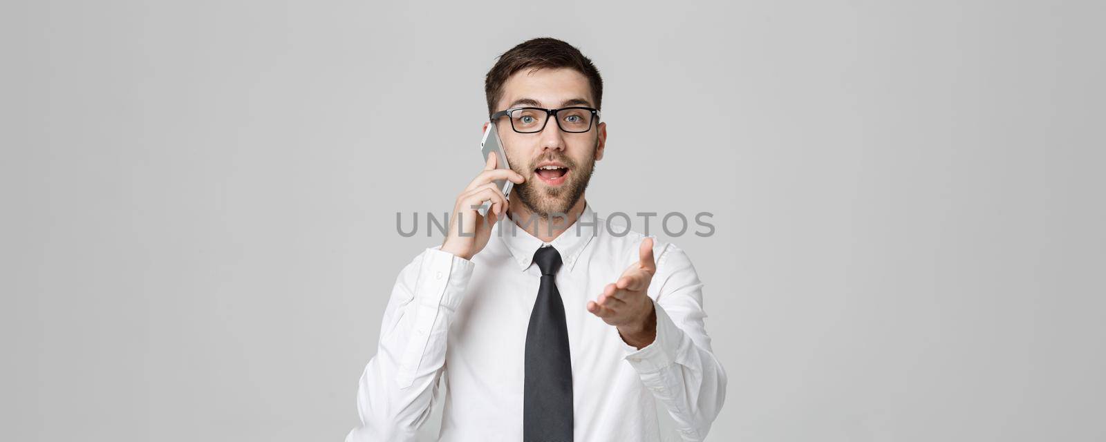 Business Concept - Portrait young handsome angry business man in suit talking on phone looking at camera. White background.