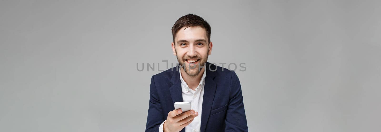 Business Concept - Portrait handsome happy handsome business man in suit playing moblie phone and smiling with laptop at work office. White Background. by Benzoix