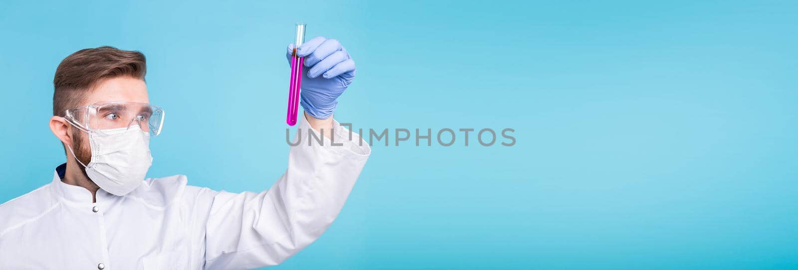 Covid-19 coronavirus, Vaccine development, pandemic, outbreak and medicine concept - Man scientist in flu mask and protective gloves holding a test tube on blue background banner with copy space by Satura86