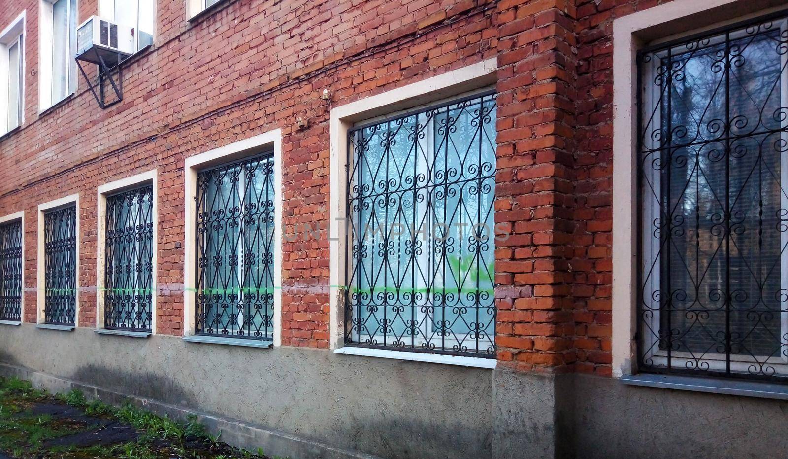 Wrought iron patterned grilles are installed outside on the first floor windows of the apartment building for safety.