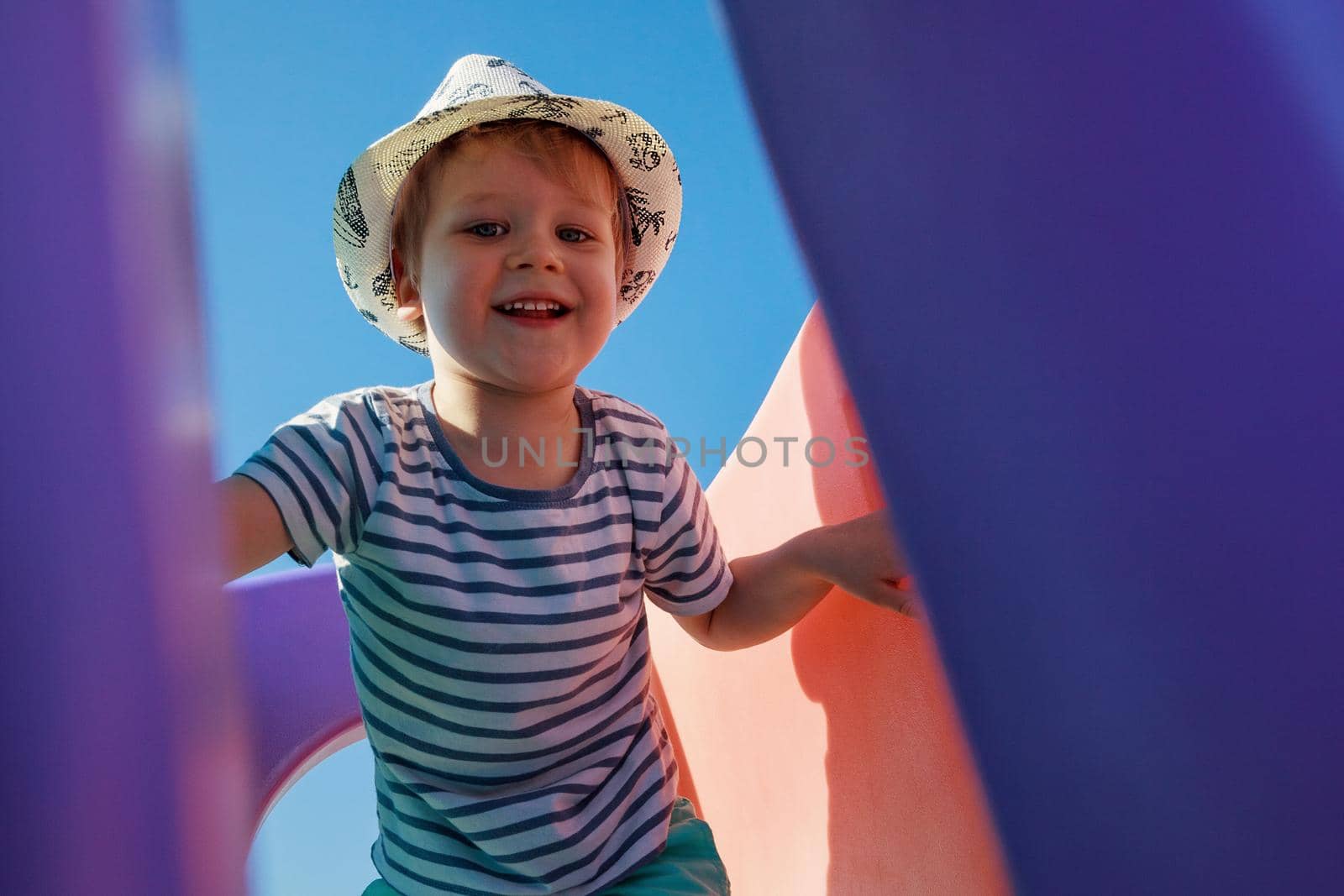 A little naughty boy runs through the plastic maze of a playground