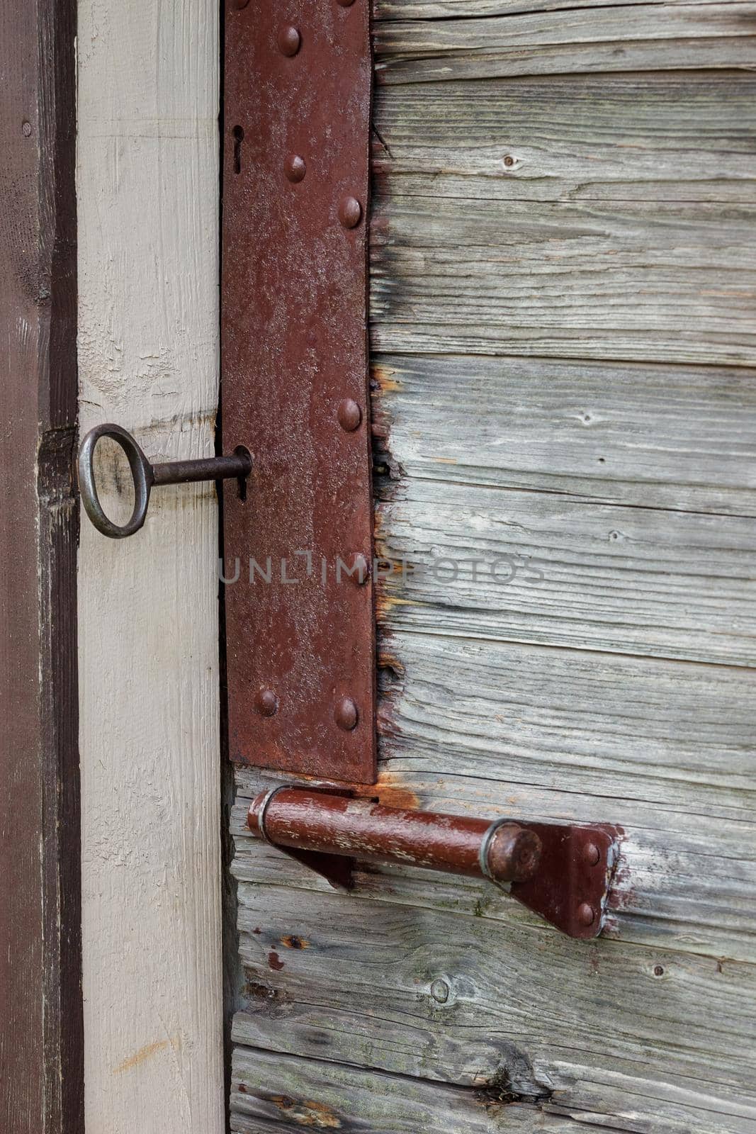 Closeup photo of an old wooden door with a big key and the lock