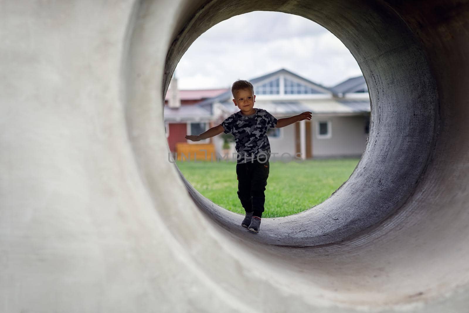 Small boy carefully going into a grey tunnel. Tunnel view. Brave kid doesn't fear anything