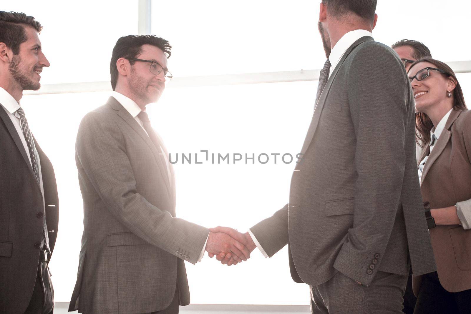 Business partners planning negotiation, exchanging contacts, thinking together about business development while standing near large window with modern urban landscape outside. Short meeting in office