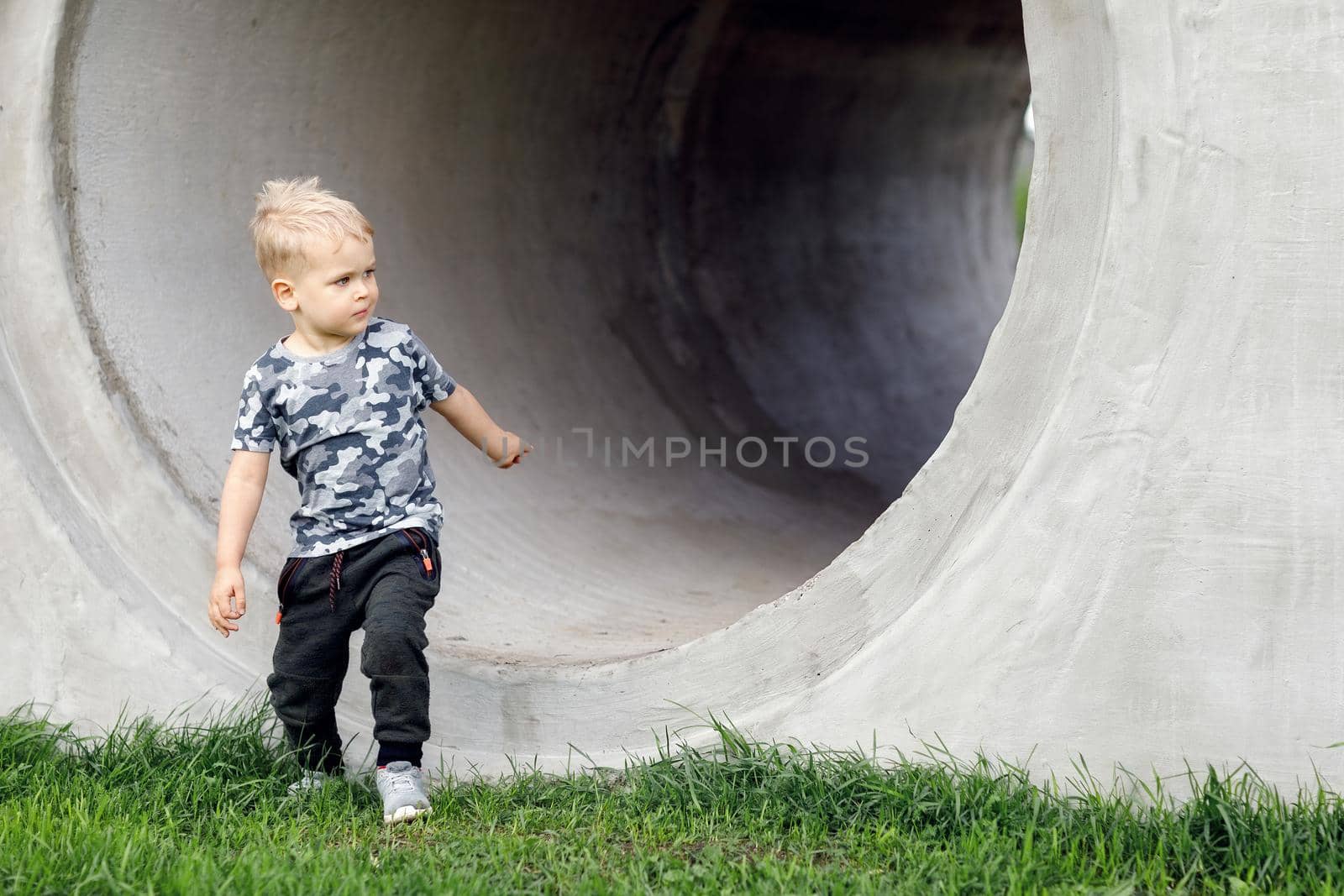 Naughty boy is going out of concrete tube by Lincikas