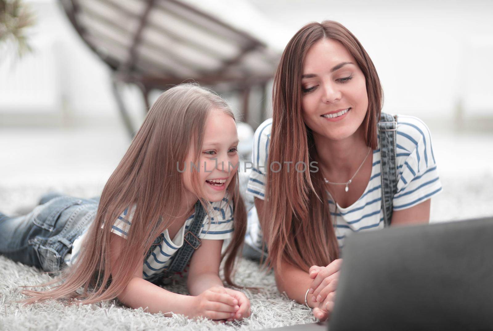 mother and daughter looking at the laptop screen. by asdf