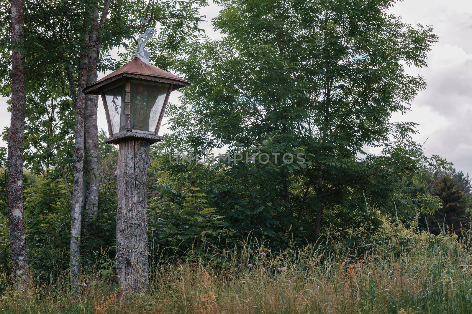 Wooden carved chapel pillar with trumpet angel on top near the way to the forest