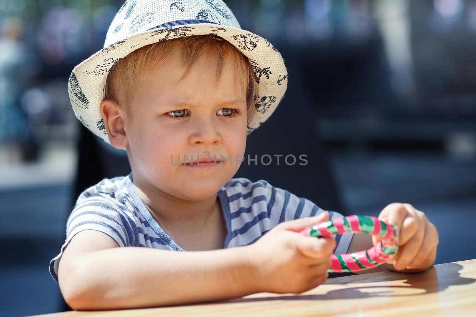 A portrait of a little boy holding a bracelet-shaped candy in his hands. City celebration and happy child.