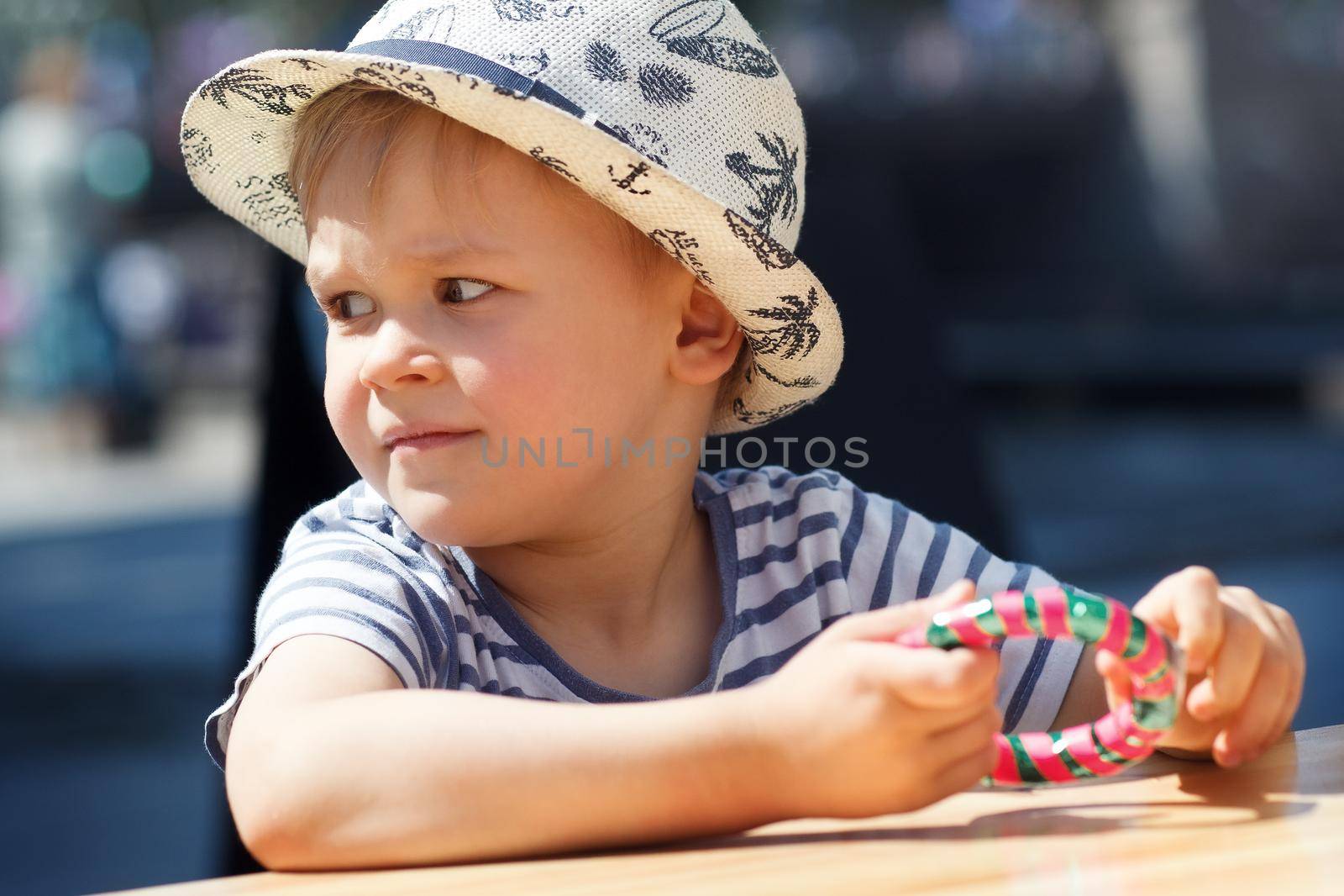 A portrait of a little boy holding a bracelet-shaped candy in his hands. City celebration and happy child. by Lincikas