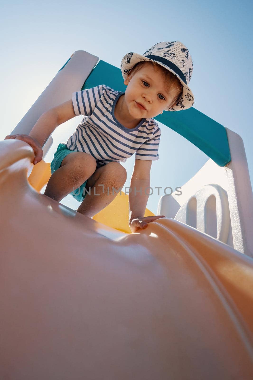 The child is getting ready to slide off the slider. by Lincikas