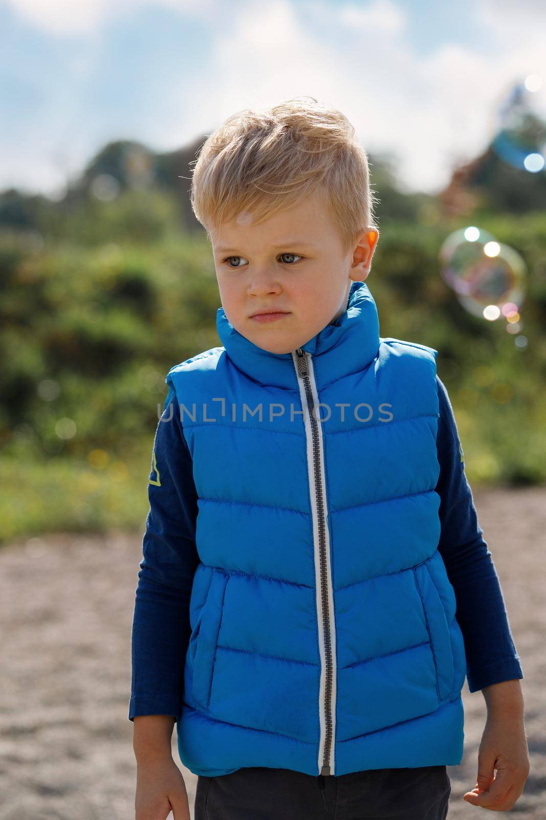 Little boy playing on the fresh air. Unhappy little boy and bubbles.