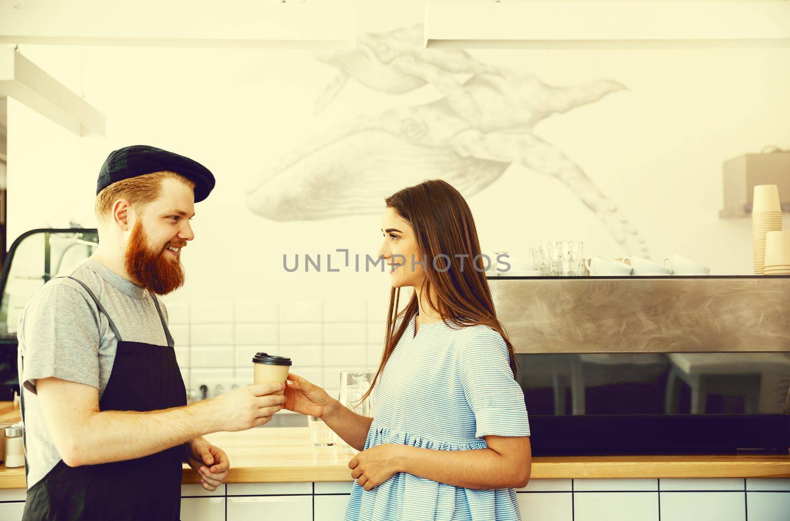 Coffee Business Concept - Positive young bearded man and beautiful attractive lady barista couple in apron.